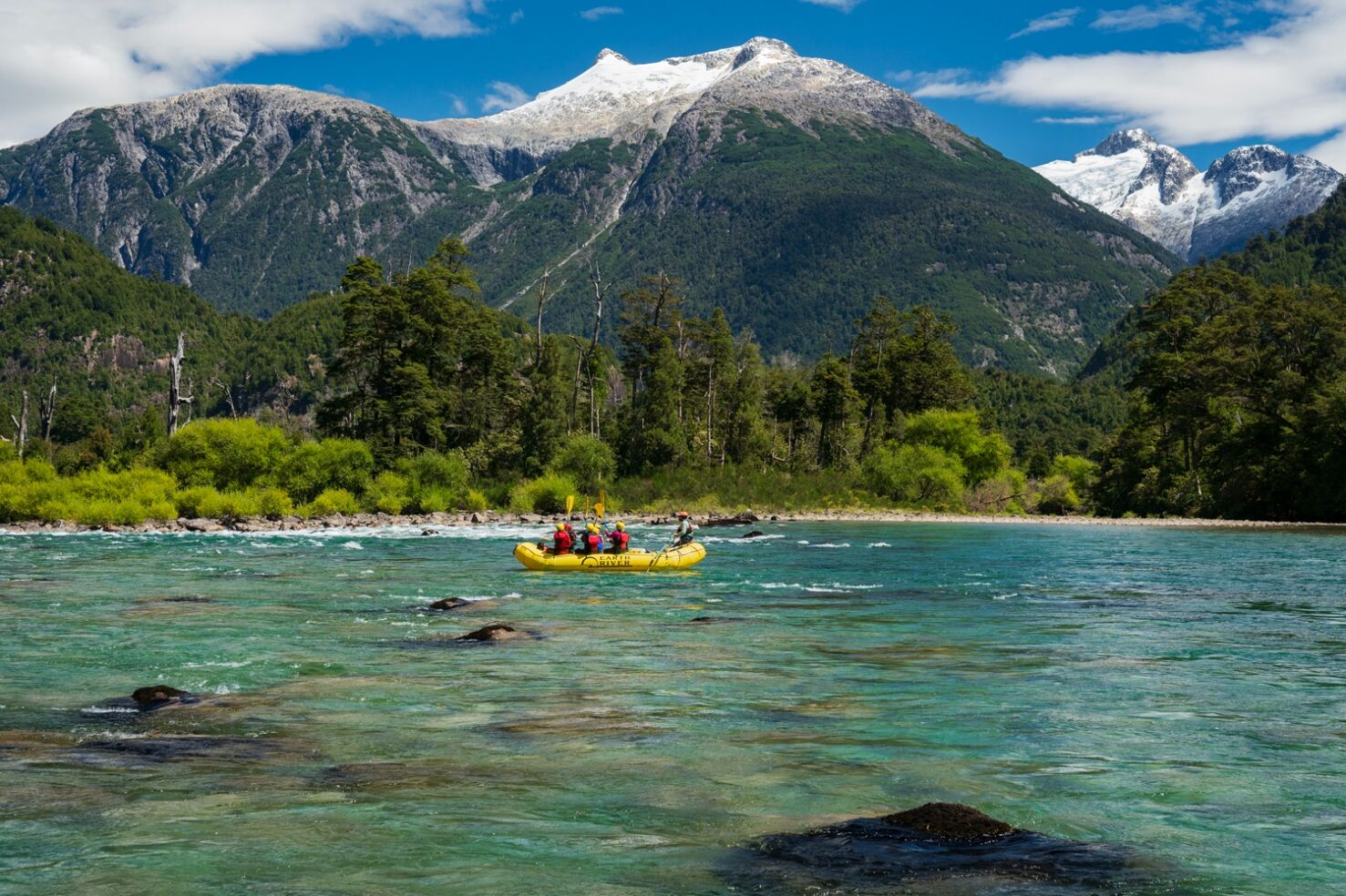Raft floating on the turquoise Futaleufú River beneath snow-capped Patagonia mountains